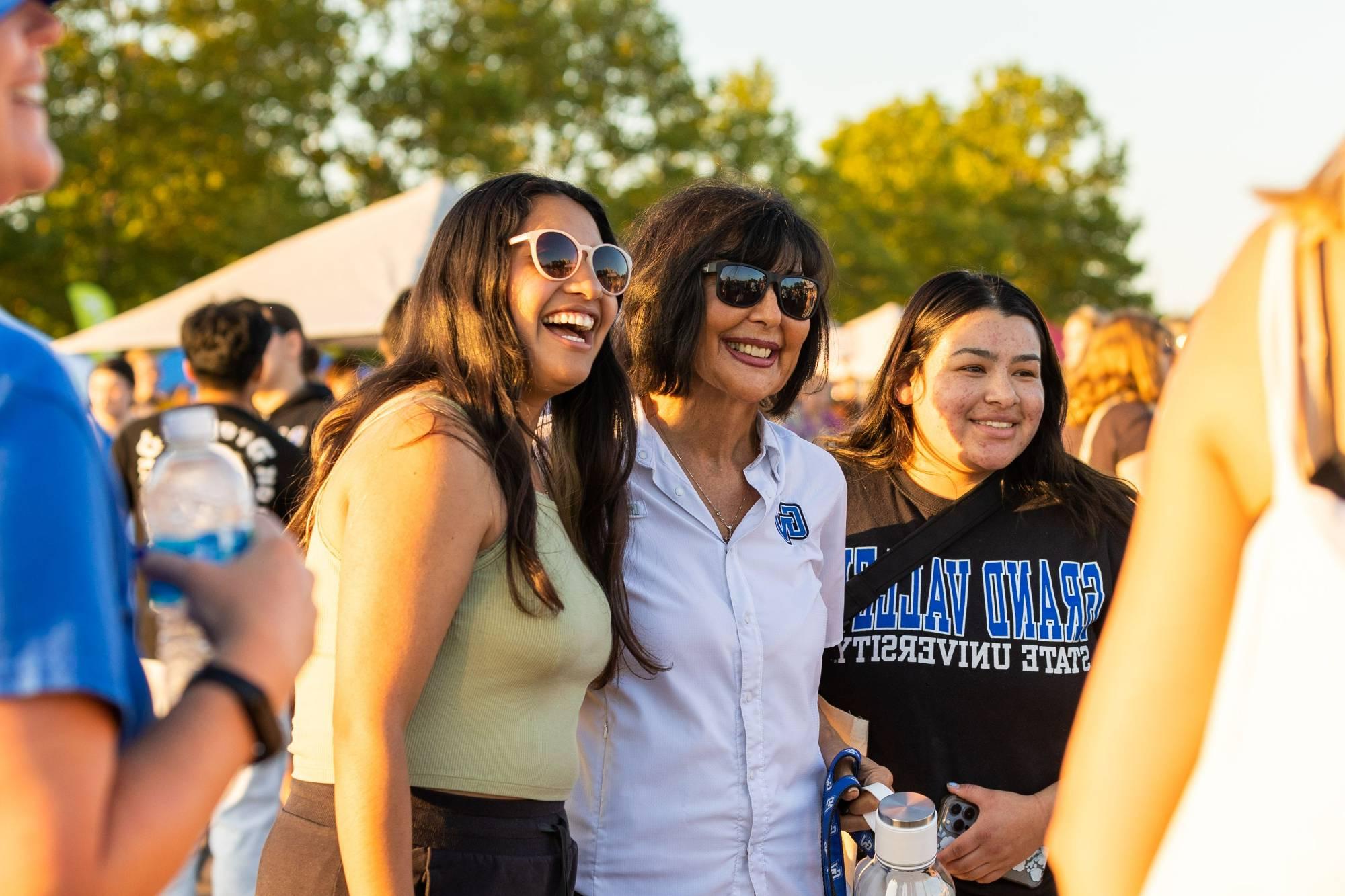 Two students take a selfie with the president of GVSU